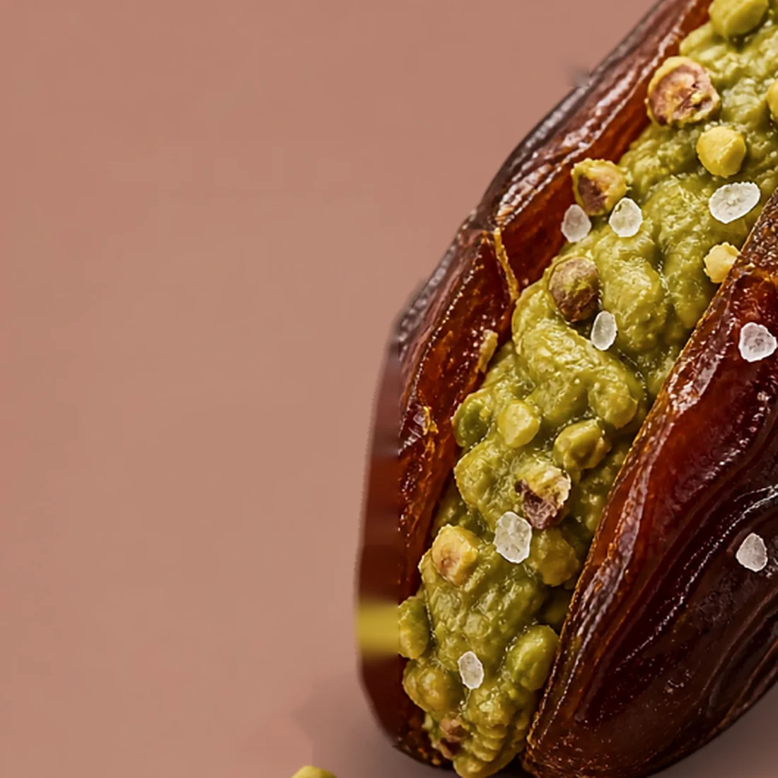 A Jumbo Medjool date split open and filled with crushed pistachio